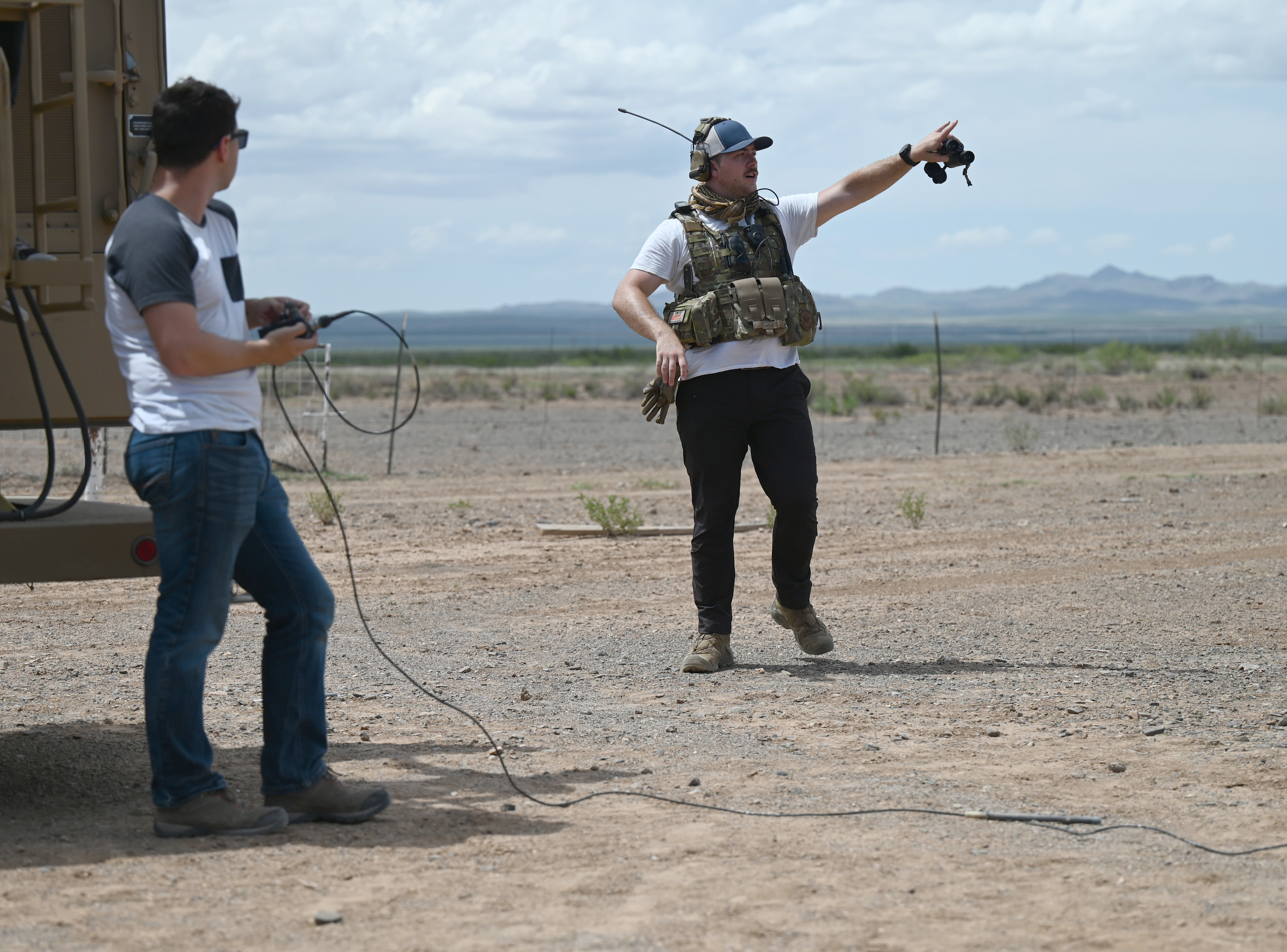 Image shows aviators using communication equipment and pointing in the desert.